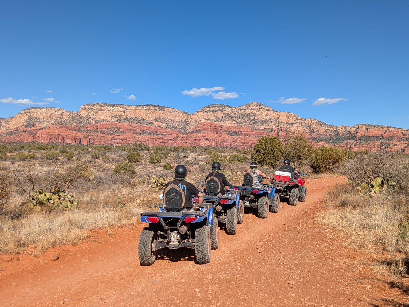 a group of people riding a motorcycle down a dirt road